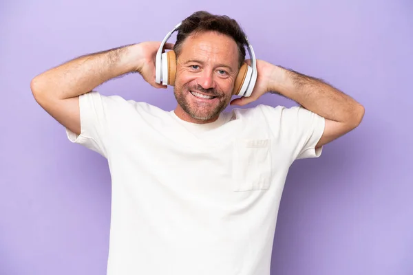 Stock image Middle age caucasian man isolated on purple background listening music