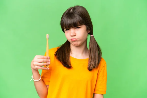 stock image Little caucasian girl brushing teeth over isolated background with sad expression