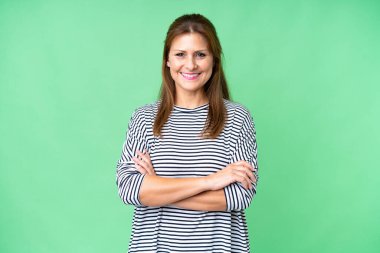 Orta yaşlı bir kadın soyutlanmış arka planda kollarını ön cephede çapraz tutuyor.