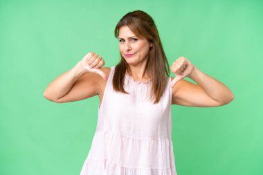 Soyutlanmış bir geçmişi olan orta yaşlı bir kadın baş parmağını iki eliyle aşağı gösteriyor.