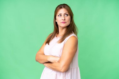 Orta yaşlı bir kadın izole bir hayat sürüyor ve kollarını kavuşturuyor.