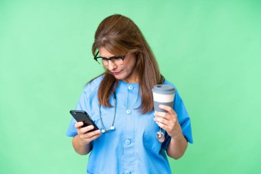 Orta yaşlı bir hemşire, izole edilmiş bir geçmişi var. Elinde kahve ve cep telefonu var.