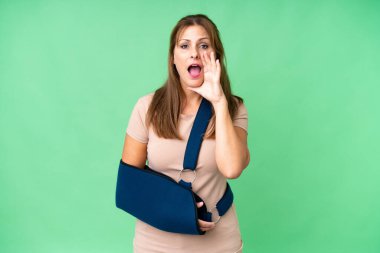 Orta yaşlı, kırık kollu ve izole edilmiş arka planda askılık takmış ağzı açık bağırıyor.