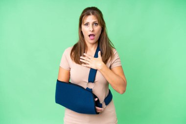 Kırık kollu orta yaşlı ve izole edilmiş arka planda askılık takan biri sağa bakarken şaşırmış ve şok olmuştu.