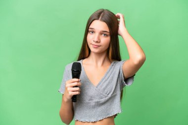 Genç şarkıcı kız izole edilmiş bir arka planda mikrofonu kaldırıp kuşkuları var.