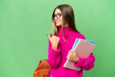 İzole edilmiş geçmişi olan beyaz bir genç kız bir ürün sunmak için kenarı işaret ediyor.