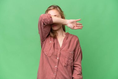 İzole edilmiş arka planda genç sarışın kadın gözlerini elleriyle kapatıyor.