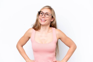 Beyaz arka planda izole edilmiş genç beyaz kadın kolları kalçasında ve gülümsüyor.