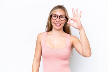 Beyaz arka planda izole edilmiş genç beyaz kadın parmaklarıyla tamam işareti gösteriyor.