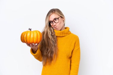 Beyaz arka planda kabak tutan genç sarışın kadın üzgün bir ifadeyle izole edilmiş.