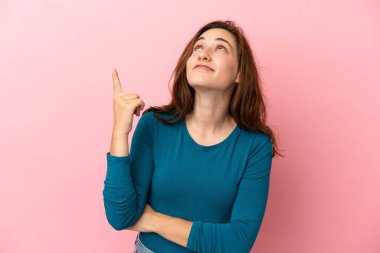 Pembe arka planda izole edilmiş beyaz bir kadın harika bir fikre işaret ediyor.