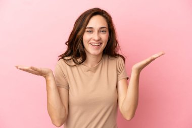 Genç beyaz kadın pembe arka planda izole edilmiş, şok olmuş yüz ifadesi var.