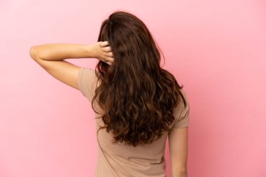 Genç beyaz kadın pembe arka planda izole edilmiş ve düşünüyor.