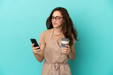 Restoran garsonunun elinde kahve ve cep telefonu var.