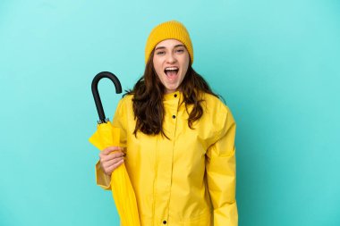 Mavi arka planda şemsiyesi olan beyaz bir adam sürpriz bir yüz ifadesiyle izole edilmiş.