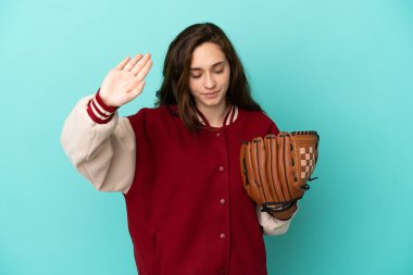 Beyzbol oynayan beyaz bir kadın mavi arka planda izole edilmiş bir şekilde durup jest yapıyor ve hayal kırıklığına uğruyor.