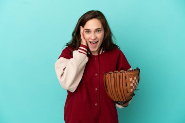 Beyzbol oynayan beyaz bir kadın mavi arka planda izole edilmiş, şaşırmış ve şok olmuş bir yüz ifadesi var.