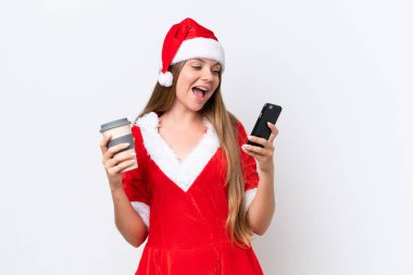 Anne Noel gibi giyinmiş genç beyaz bir kadın beyaz arka planda izole edilmiş. Elinde kahve ve bir cep telefonu var.