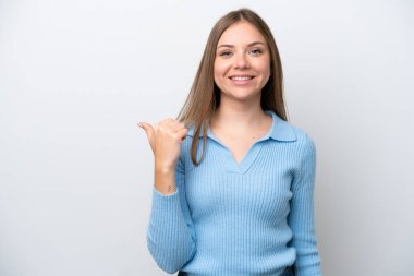 Beyaz arka planda izole edilmiş genç Litvanyalı kadın bir ürünü sunmak için kenarı işaret ediyor