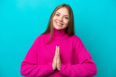 Mavi arka planda izole edilmiş genç Litvanyalı kadın avuç içlerini bir arada tutuyor. İnsan bir şey ister.