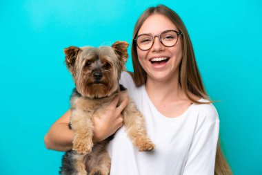 Mavi arka planda köpeği tutan Litvanyalı genç bir kadın.
