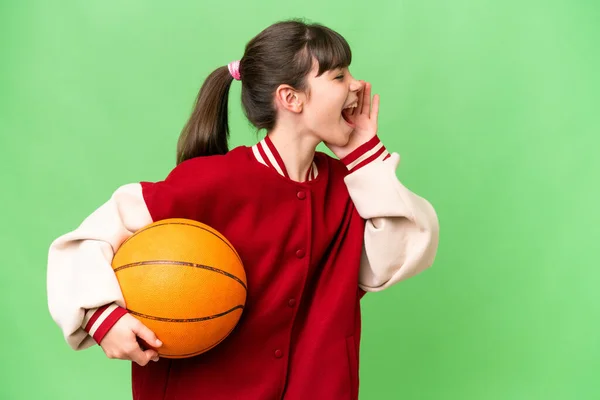 小さいですCaucasian女の子プレイバスケットボール上の隔離された背景叫びとともに口をワイドオープンへザ側 — ストック写真