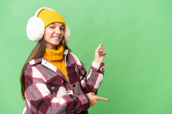 年少无知的高加索女孩 戴着冬衣 披着孤立的背景 手指指向侧面 并展示了一种产品 — 图库照片