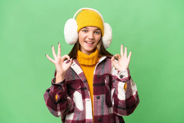 年轻的高加索女孩 戴着冬衣 站在与世隔绝的背景上 手指头上有个好的标志 — 图库照片