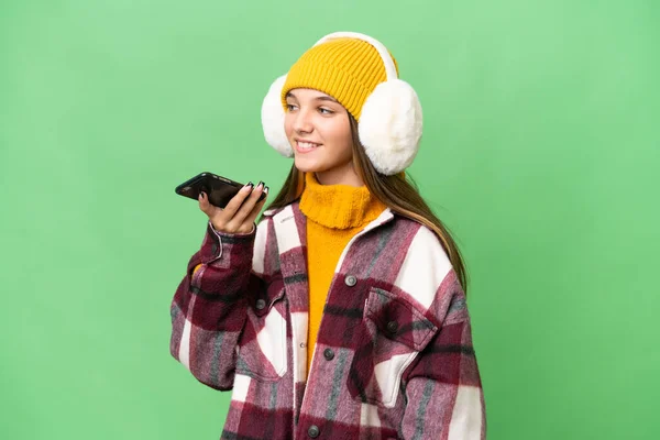 年轻的高加索女孩穿着冬衣 背景偏僻 用手机与人交谈 — 图库照片