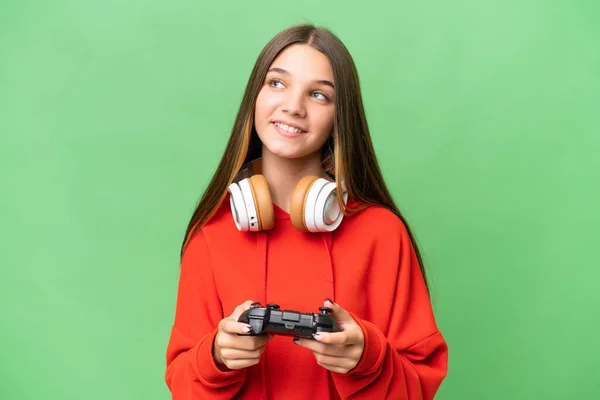 青少年白种人女孩在玩电子游戏控制器时超越了孤立的背景 一边抬头一边思考着一个想法 — 图库照片