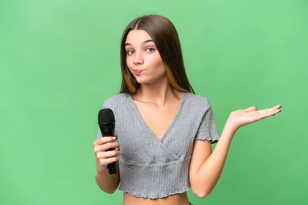 Adolescente Cantante Chica Recogiendo Micrófono Sobre Aislado Fondo Teniendo Dudas — Foto de Stock