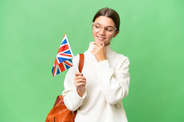 十几岁的学生高举英国国旗 背景孤寂 面带微笑地朝旁边望去 — 图库照片
