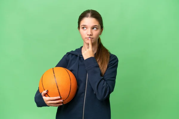 ティーンCaucasian女の子プレイバスケットボール上の隔離された背景を持っています疑問を持っています上へ見ます — ストック写真