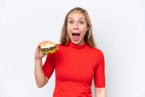 stock image Young blonde woman holding a burger isolated on white background with surprise and shocked facial expression