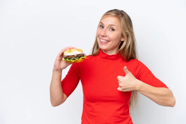 Young Blonde Woman Holding Burger Isolated White Background Thumbs Because — Stock Photo, Image