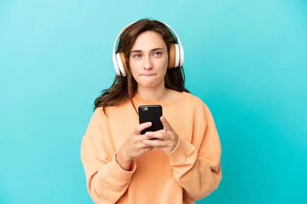Joven Mujer Caucásica Aislada Sobre Fondo Azul Escuchando Música Con —  Fotos de Stock