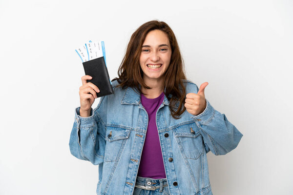 Young caucasian woman isolated on white background in vacation holding a passport and plane with thumb up