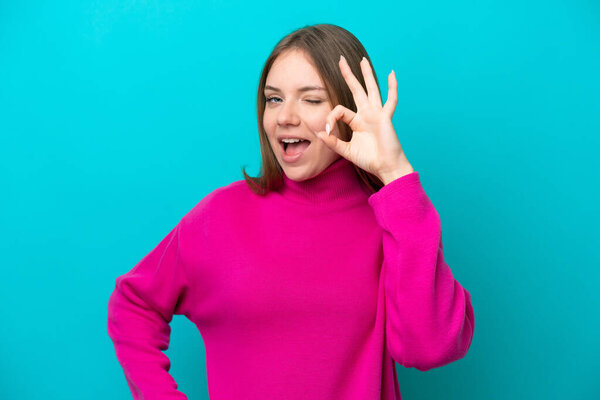 Young Lithuanian woman isolated on blue background showing ok sign with fingers