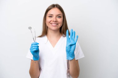 Beyaz arka planda izole edilmiş aletleri tutan dişçi kadın mutlu ve parmaklarıyla dört tane sayıyor.