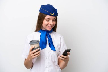 Litvanyalı uçak hostesi beyaz arka planda izole edilmiş. Elinde kahve ve cep telefonu var.