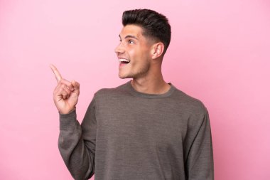 Pembe arka planda izole edilmiş genç beyaz adam çözümü bulmak için parmağını kaldırıyor.