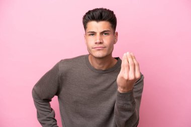 Pembe arka planda izole edilmiş genç beyaz adam İtalyan jestleri yapıyor.