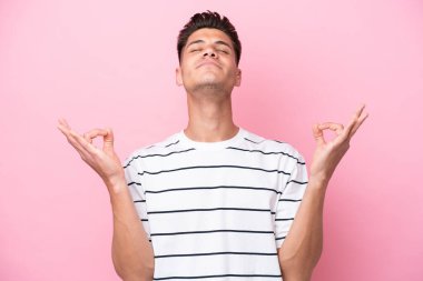 Zen pozisyonunda pembe arka planda izole edilmiş genç beyaz bir adam.