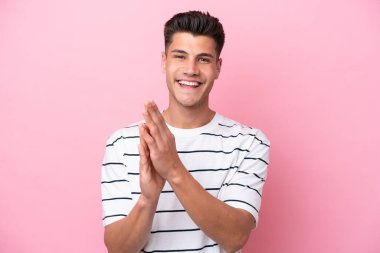 Pembe arka planda izole edilmiş genç beyaz adam bir konferanstan sonra alkışlıyor.