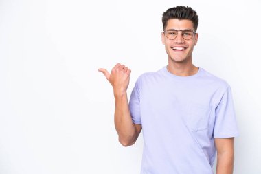 Beyaz arka planda izole edilmiş genç beyaz bir adam bir ürün sunmak için kenarı işaret ediyor.