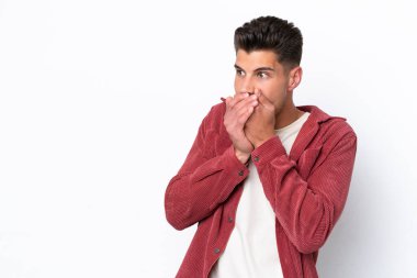 Beyaz arka planda izole edilmiş genç beyaz adam ağzını kapatıyor ve yan tarafa bakıyor.