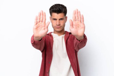 Beyaz arka planda izole edilmiş genç beyaz adam dur hareketi yapıyor ve hayal kırıklığına uğruyor.