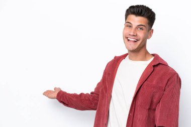 Beyaz arka planda soyutlanmış beyaz tenli genç adam davet edilmek için ellerini yana uzatıyor.