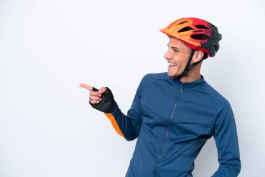 Beyaz arka planda izole edilmiş genç bir beyaz bisikletçi parmak göstererek bir ürün sunuyor.