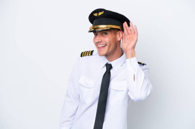Kafkasyalı uçak pilotu beyaz arka planda izole edilmiş bir şekilde elini kulağına koyarak bir şey dinliyor.